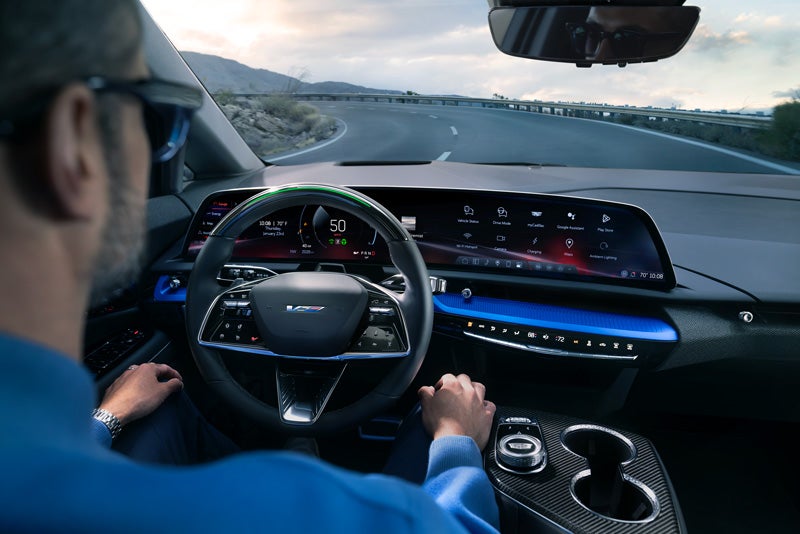 Front View of the 2026 OPTIQ-V Driving Through the Dusk Utilizing its Headlights | Three-Way Cadillac in Bakersfield CA