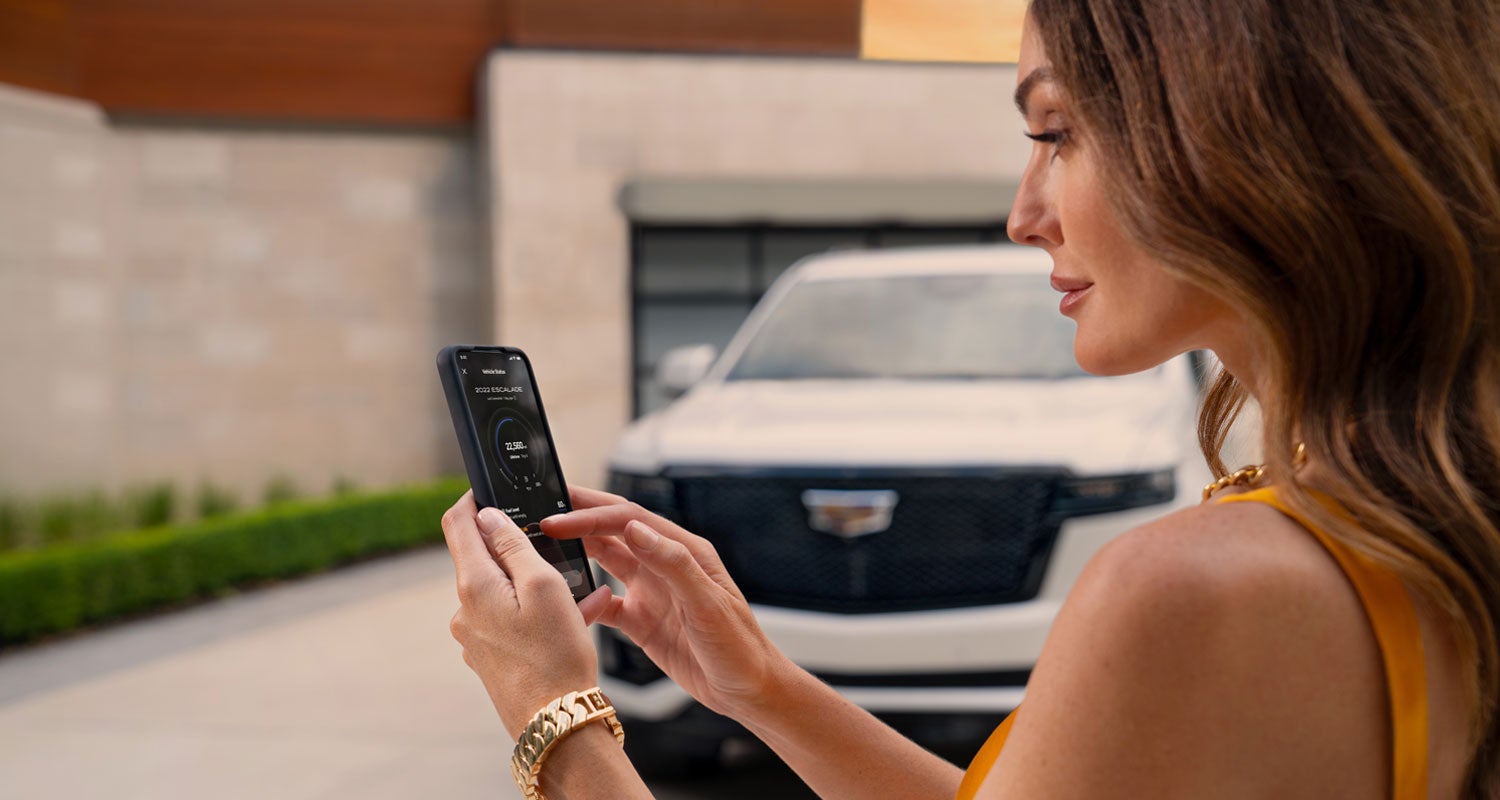 lady checking her mobile with a Cadillac vehicle background | Three-Way Cadillac in Bakersfield CA